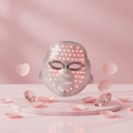 LED Light Therapy Face Mask on pink marble with rose petals